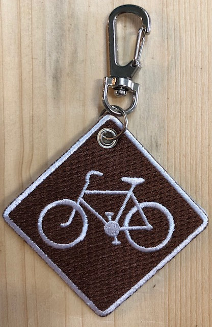 Embroidered key clip with a bicycle on it.