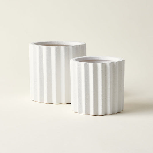Set of two white ceramic planters with a fluted texture.