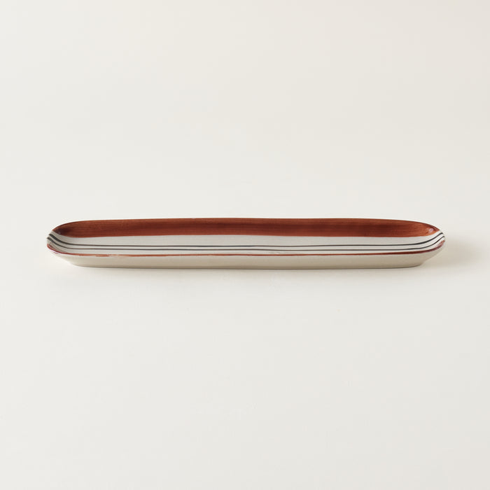 Oval stoneware tray with a hand-painted black and deep orange striped design.