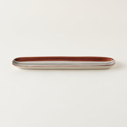 Oval stoneware tray with a hand-painted black and deep orange striped design.