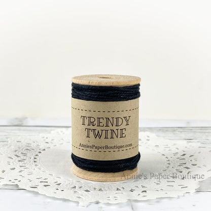 Solid black cotton twine wrapped around a wooden spool sitting on a white background.
