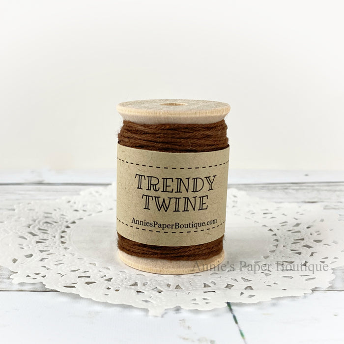 Solid brown cotton craft twine wrapped around a wooden spool sitting on a white background